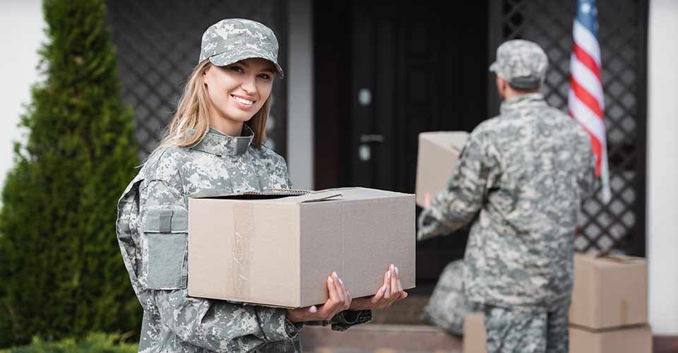 Smiling military woman holding cardboard box on moving day