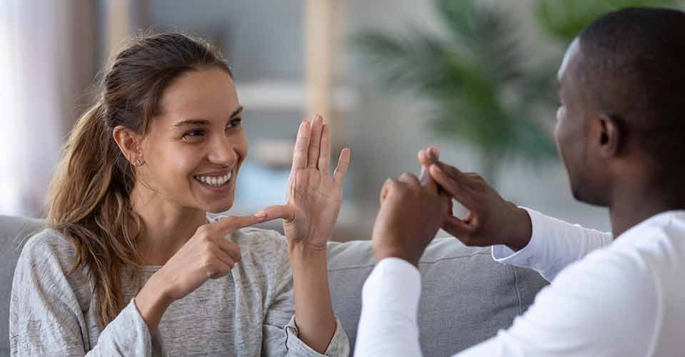 Smiling mixed ethnicity couple talking with sign language