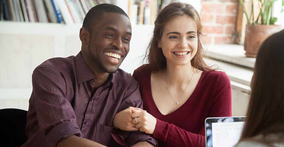Smiling multiracial couple talking with mortgage broker