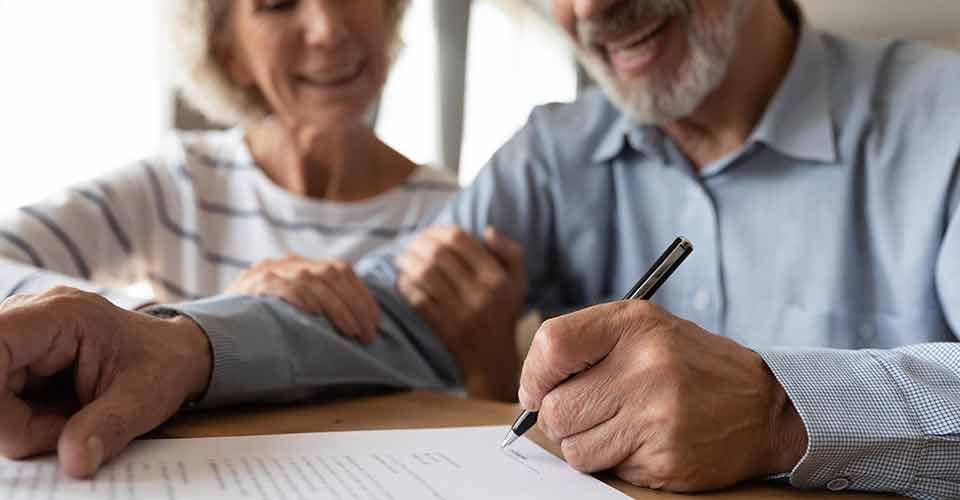 Smiling old mature couple put signature on home purchase document