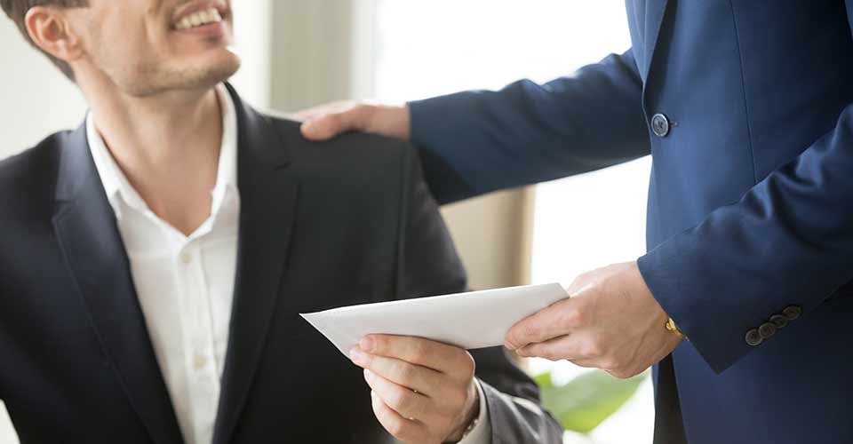 Someone giving gift money in paper envelope to happy smiling man