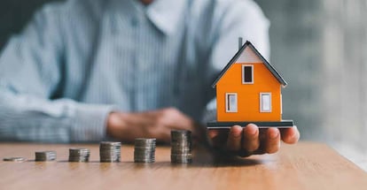 Stack of coins and home model for investment