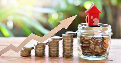 Stack of coins and model house on top