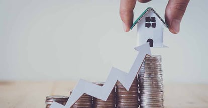 Stack of coins for real estate investment and house made from paper cardboard