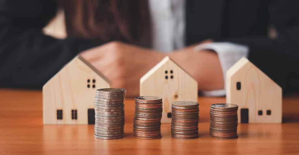 Stack of money and home models for real estate investment