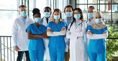 Team of male and female nurses crossing hands in hospital