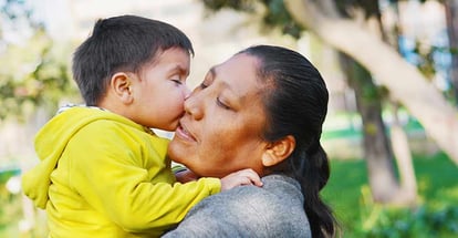 Tender portrait of little son kissing his mommy