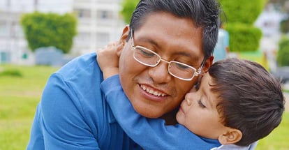 Tender portrait of native american man with his little son in the park