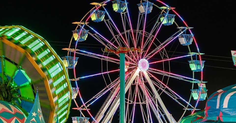 The bright and colorful lighted Ferris Wheel at the childrens state and county fair off southern boulevard in West Palm Beach Florida