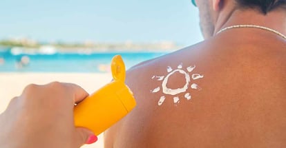 The girl on the beach applies sunscreen to the skin of a man