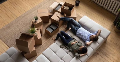 Top view of a happy couple homeowners relaxing on couch