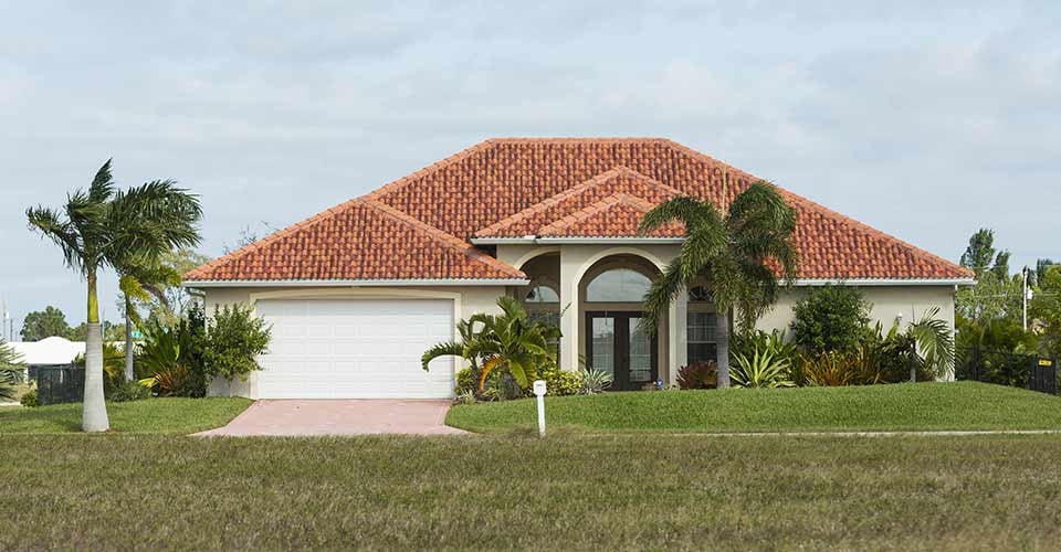 Typical Southwest Florida concrete block and stucco home in the countryside with palm trees tropical plants and flowers