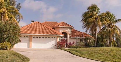 Typical Southwest Florida concrete block and stucco home in the countryside with palm trees