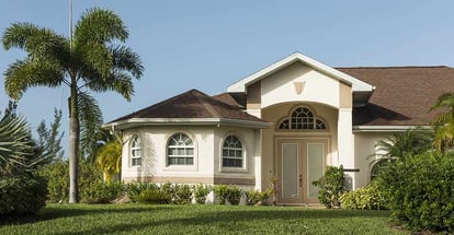 Typical Southwest concrete block and stucco home in the countryside with palm trees and grass lawn in Florida