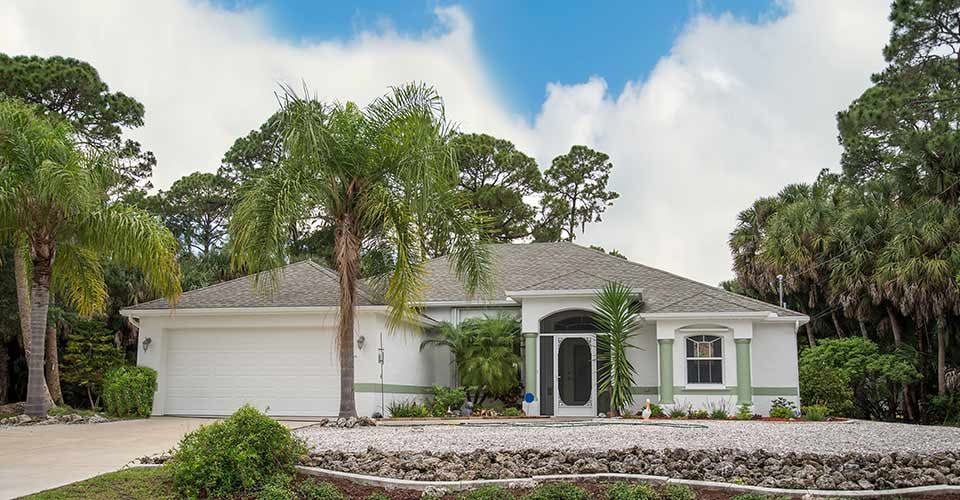 Typical concrete block and stucco home in the countryside with palm trees in Florida