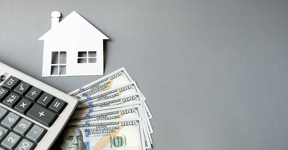 White paper house with dollars banknotes and calculator
