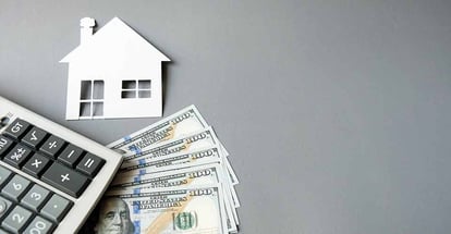 White paper house with dollars banknotes and calculator