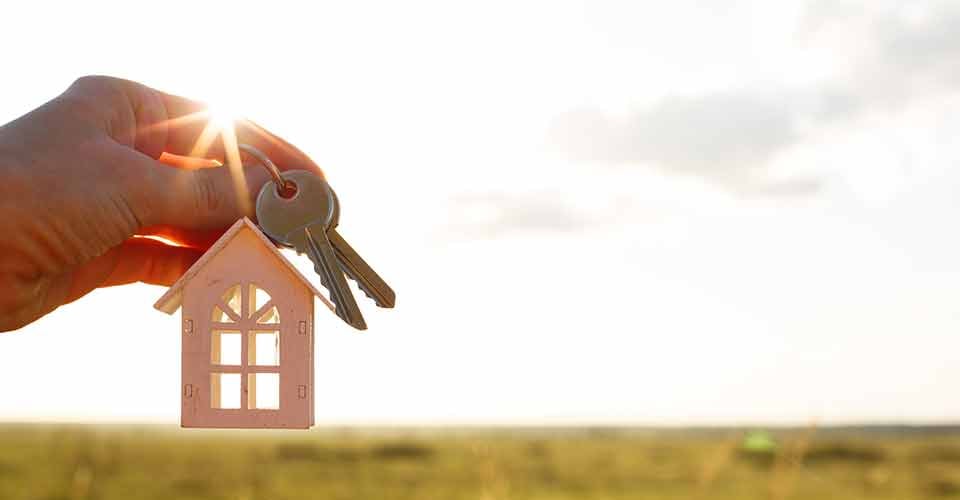 White wooden model house and keys in hand