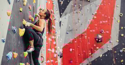 Woman climbing on artificial wall indoors