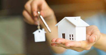 Woman holding house model and key in hand after home loan approval