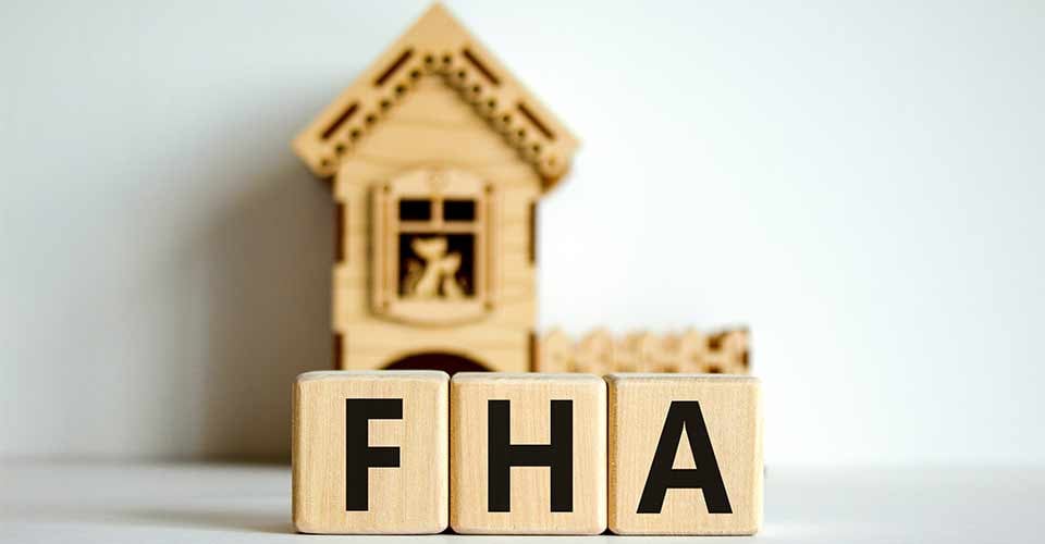 Wooden cubes form the word FHA near miniature house