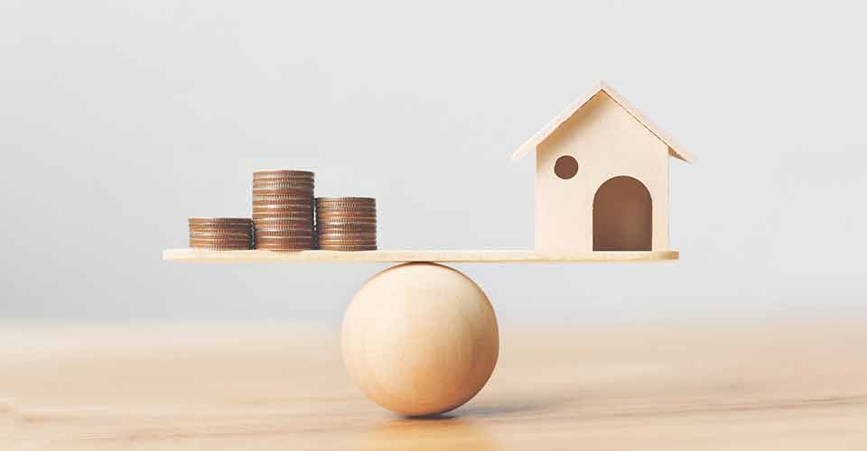 Wooden home and money coins stack on wood scale