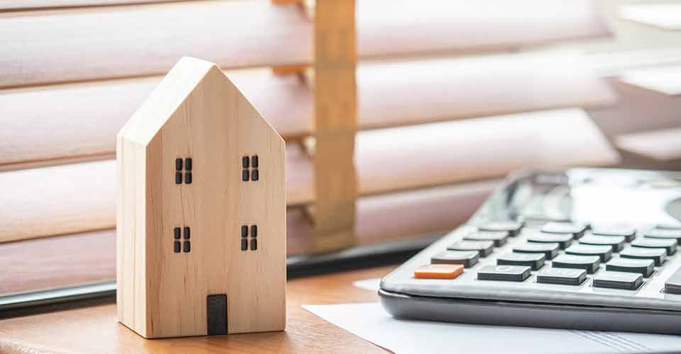 Wooden house model calculator and notebook on office desk