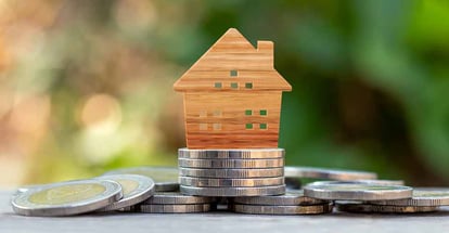 Wooden house model on coin pile