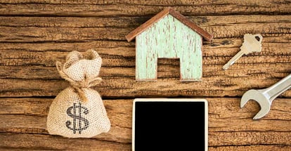 Wooden model house and money bag with construction tools for home renovation