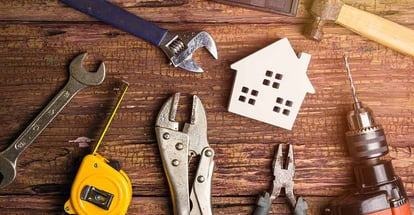 Wooden white house toy and construction tools on wooden background