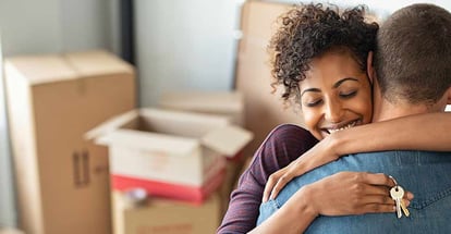 Young african woman holding home keys while hugging boyfriend in their new home