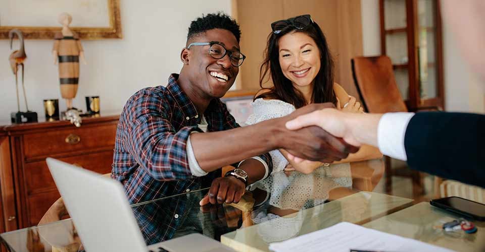 Young couple handshaking real estate agent after signing contract