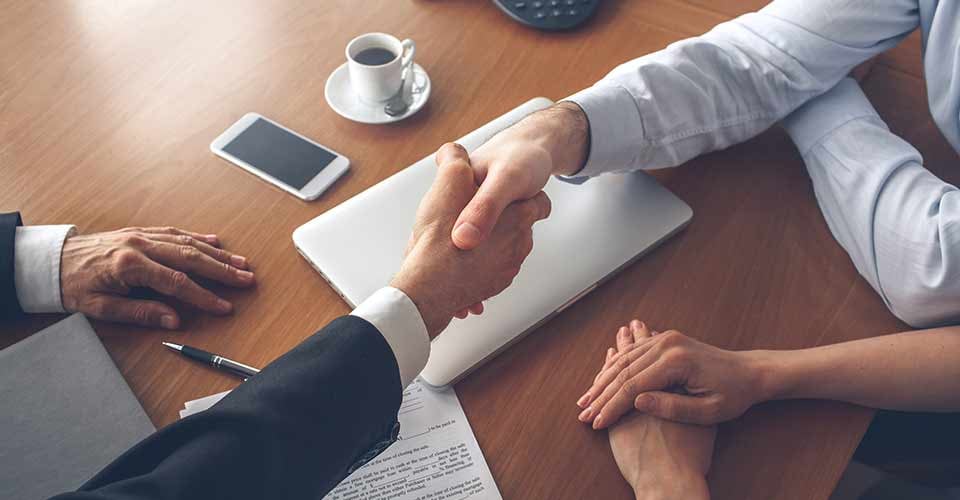 Young couple shaking hand with realtor after signing home purchase agreement