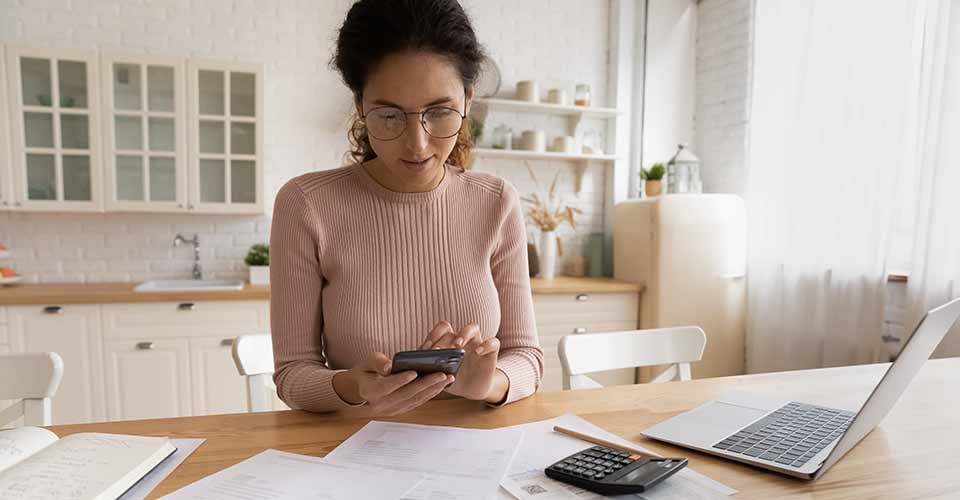 Young female calculating rental income with financial papers on table