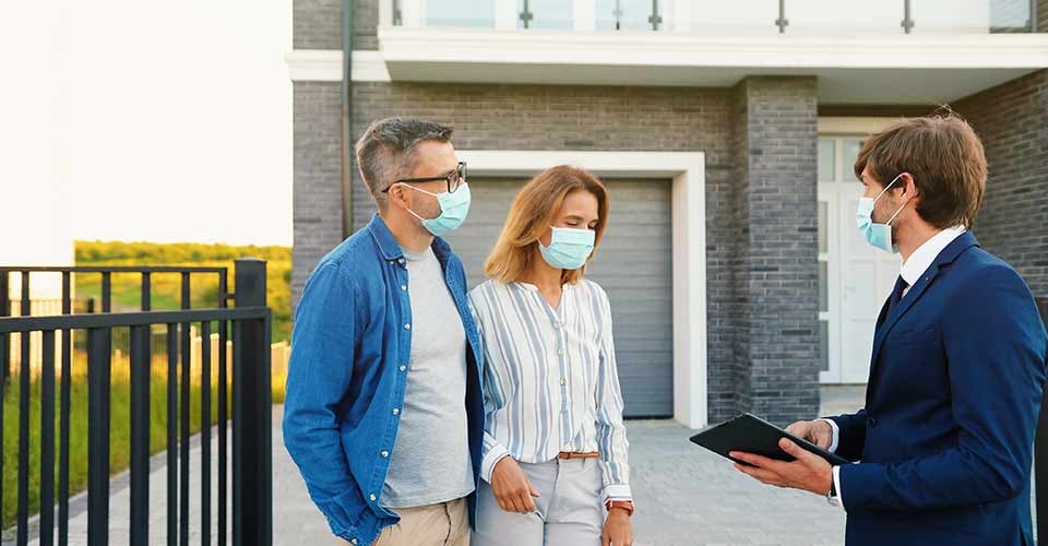 Young happy couple buying house at outskirt and talking with male real estate agent