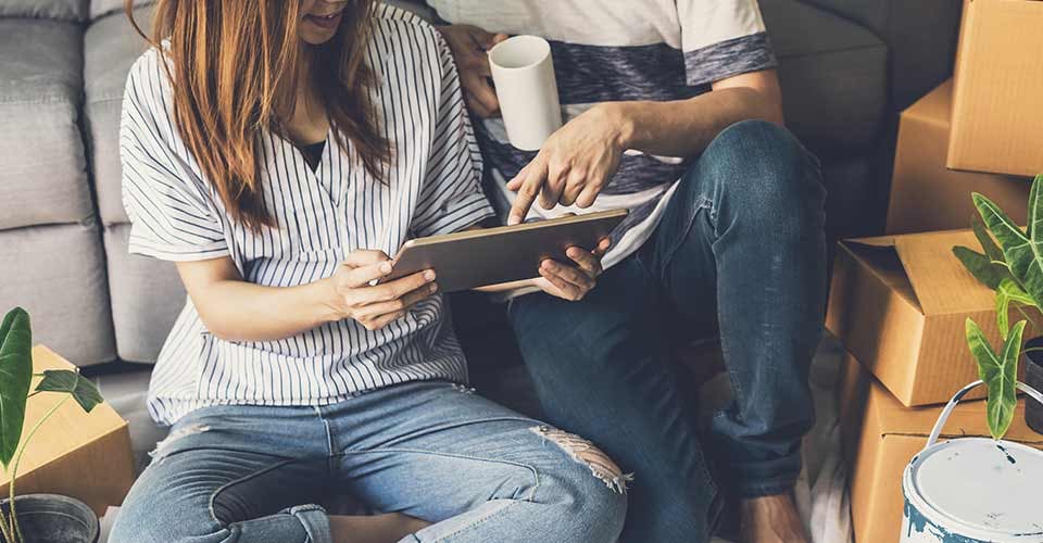 Young happy homeowner couple moving into new house sitting and relaxing on the floor