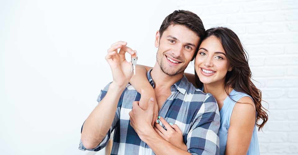 Young smiling couple showing keys to new home