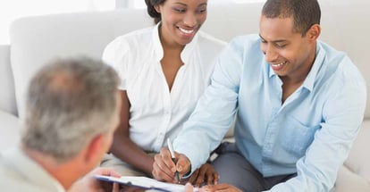 Young smiling couple signing contract on the couch in the office