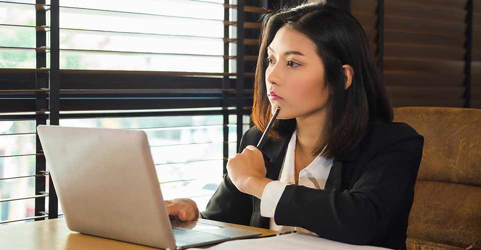 Young woman in formal suit looking at mortgage document on laptop