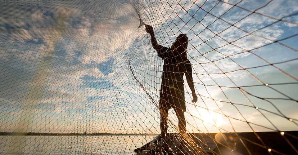 A fisherman cast a net at lake in the morning time