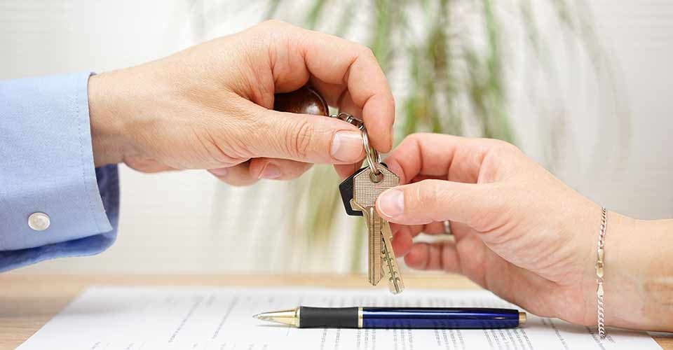 Real estate agent gives house keys to his client after signing contract