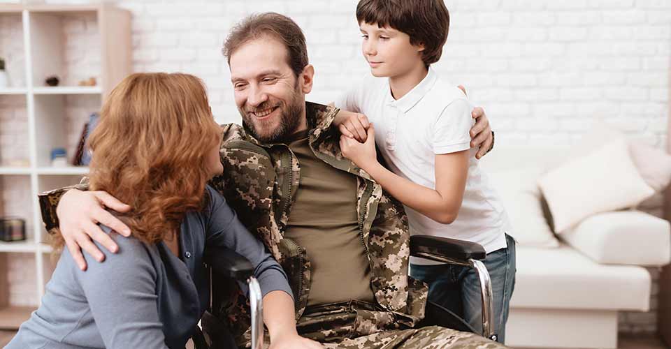 A man in uniform in a wheelchair with his family
