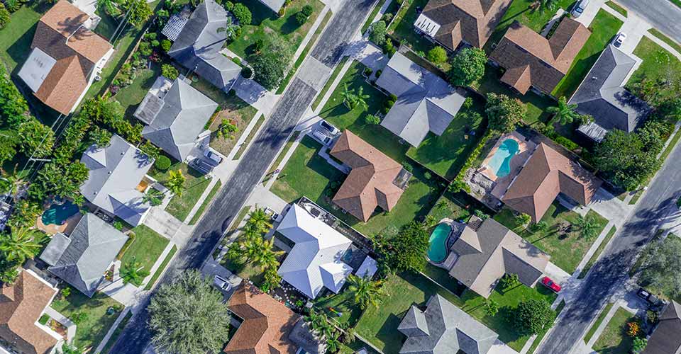 Aerial view of warm sunny neighborhood community and lots of houses with pools and palm trees