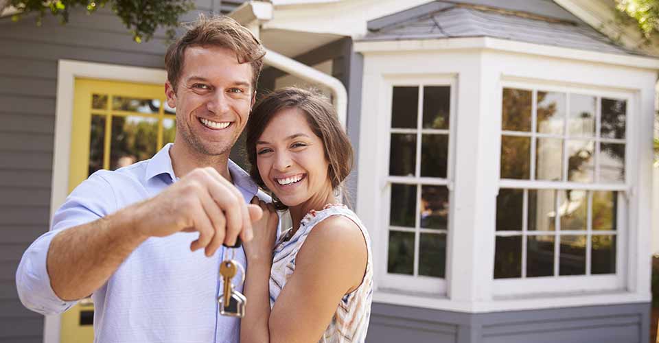 Couple With Keys Standing Outside New Home