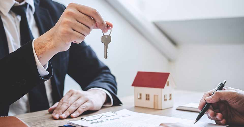 Estate agent giving house keys to client after signing agreement contract