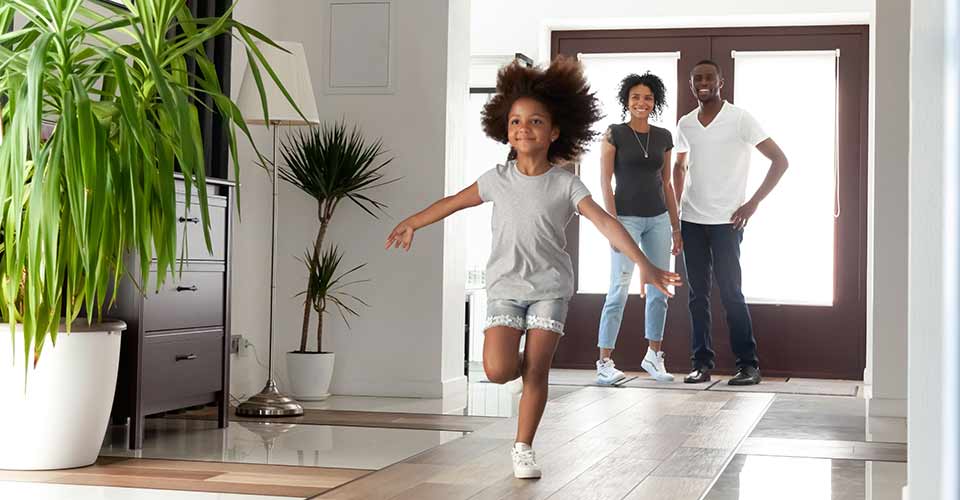 Happy black parents and kid daughter coming into new home