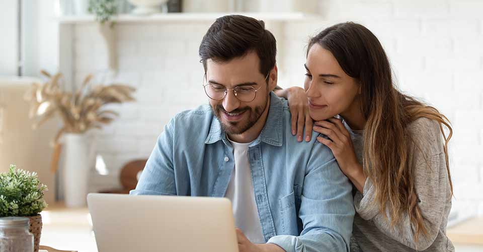 Happy young couple using laptop to learn about home purchase in Florida
