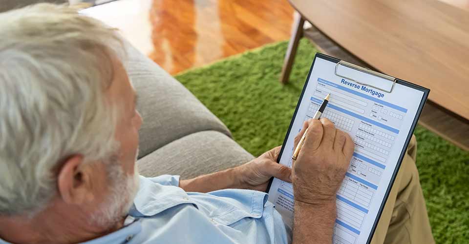 Senior old man elderly reading and examining reverse mortgage application form
