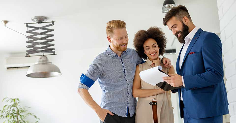 Young couple with real estate agent buying a new house